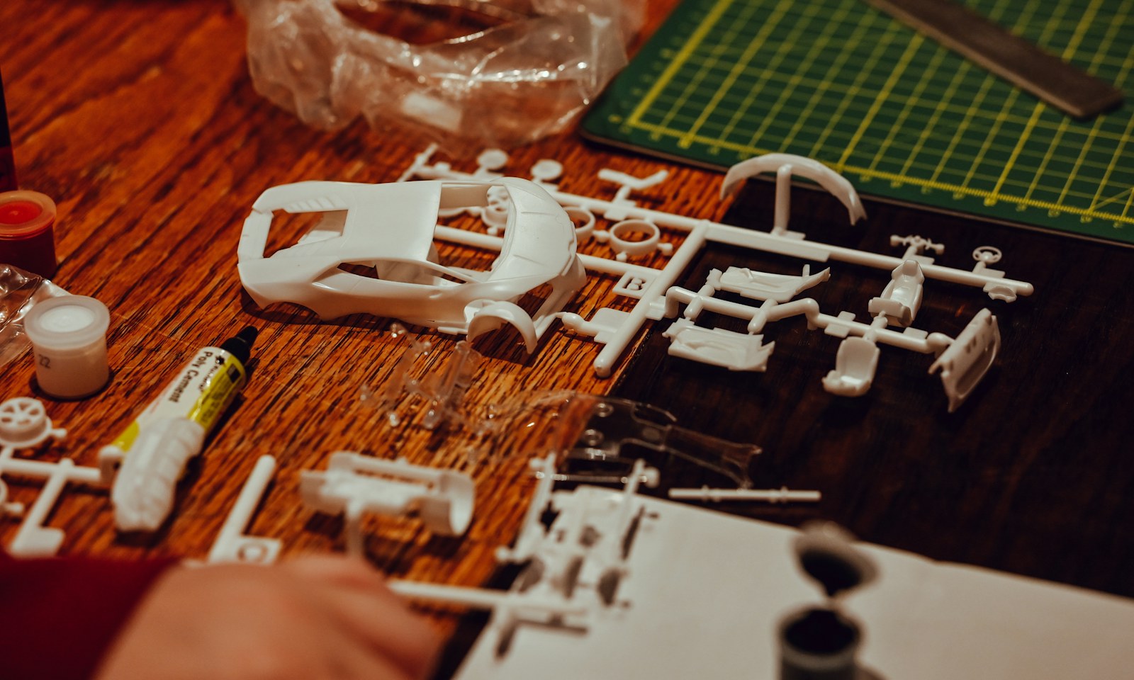 Części modelu plastikowego samochodu i mata do cięcia na stanowisku modelarza