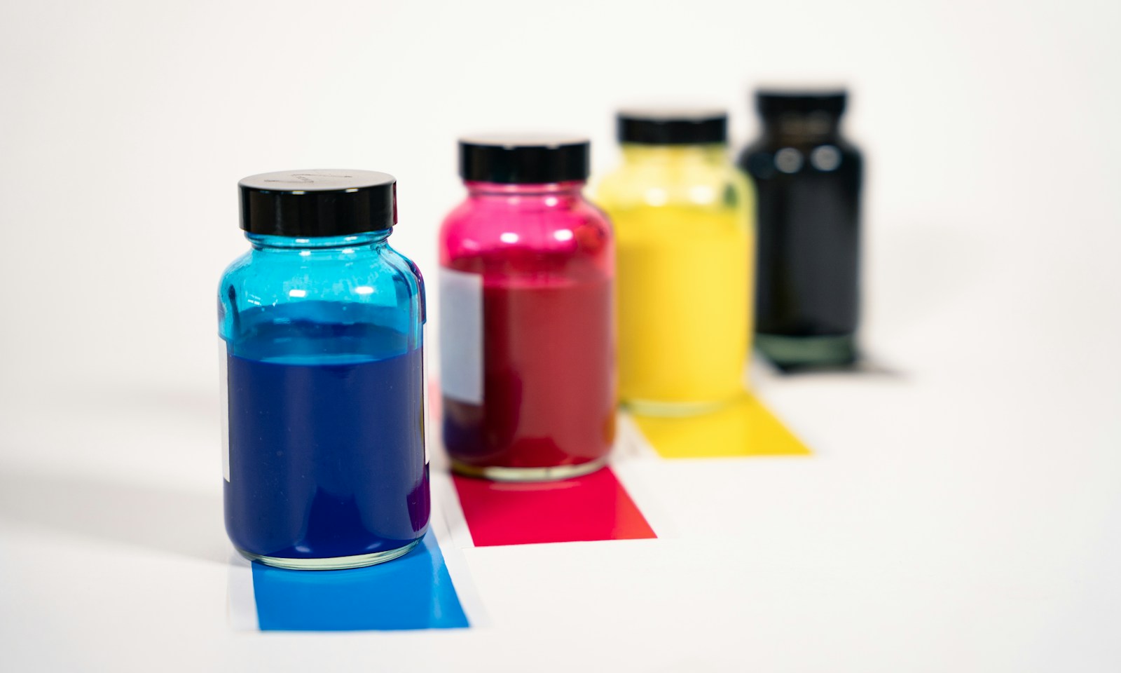 Cztery słoiki z tuszem w kolorach cyan, magenta, żółtym i czarnym